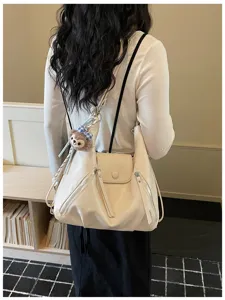 Detailed view of a trendy Korean style beige leather shoulder tote bag with charm.