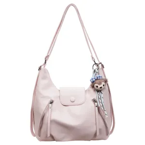 Pink multi-way leather shoulder bag and backpack with cute plush charm for women daily use.
