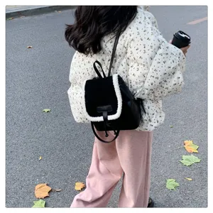 Detail view of black and white plush backpack worn outdoors, showcasing casual texture.