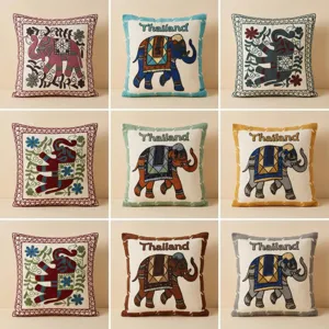 Vue détaillée de housses de coussin brodées d'éléphants style thaïlandais traditionnel chic.