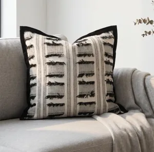 Close-up detail of the black and white woven throw pillow with black velvet border and tassels.