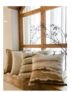 Detailaufnahme kuscheliger Plüsch- und Strickkissen in warmen Tönen, ideal für Sofa oder Ferienhaus.