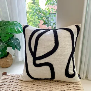 Detail shot of decorative throw pillow with abstract black tufted lines on beige fabric for sofa.