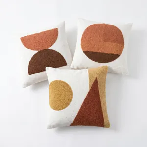 Vue détaillée d'une housse de coussin touffetée géométrique moderne au motif abstrait.