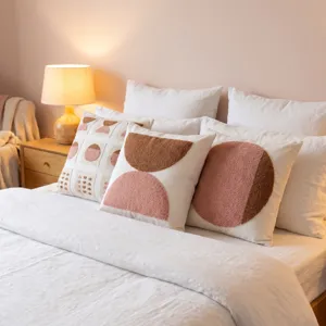 Housse de coussin decorative touffetee au design geometrique moderne pour canape et lit.