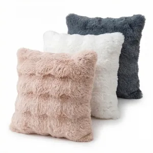 Set of three luxurious fluffy faux fur plush pillows in pink, white and dark grey colors.