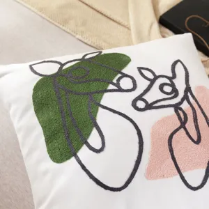 Close-up of modern abstract embroidery throw pillow cover with green and pink patches.