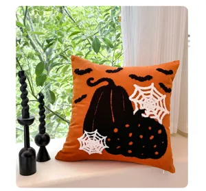 Coussin décoratif brodé pour Halloween avec citrouilles noires et toile d'araignée.