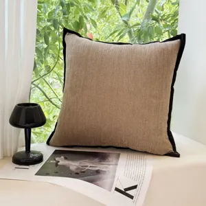 Vintage art style cushion detail, textured fabric with black border, cozy sofa decor prop.