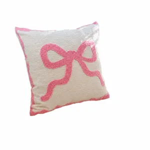 Pink bow throw pillow with textured fabric and scalloped edge for living room sofa decor.