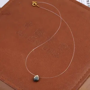 Detailed close-up view of the invisible fishing line necklace featuring a dark teardrop shell pendant.