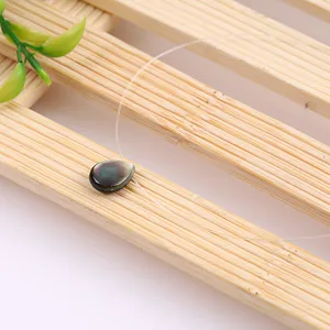 Close-up detail of teardrop shell pearl necklace on clear invisible fishing line cord.