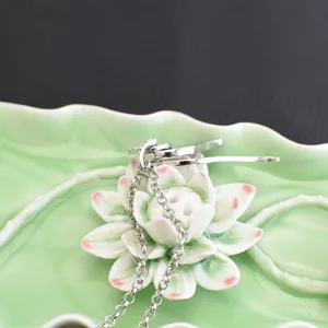 Exquisite silver necklace close-up view presented on a decorative lotus leaf ceramic dish.