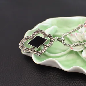 Detail shot of retro Thai silver pendant necklace with black stone and ornate vintage design.