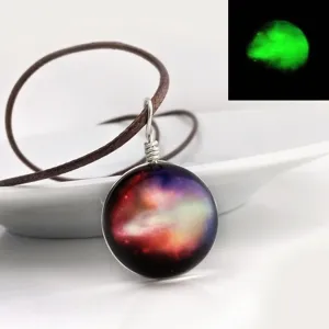 Closeup of glowing galaxy glass pendant necklace with brown cord and star pattern design.