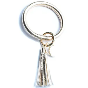 Gouden lederen armband sleutelhanger met kwastje en metalen hanger, detailweergave.