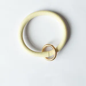 Detailweergave van de ronde PU lederen polsband sleutelhanger met gouden metalen ring.