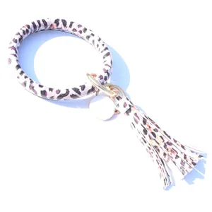 Bracelet porte-clés cercle en cuir imprimé léopard avec pompon et pendentif disque métal.