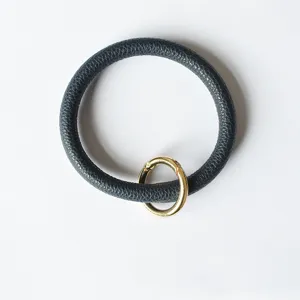 Detailopname van de donkerblauwe PU-leder polsband sleutelhanger met gouden ring.