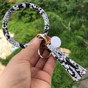 Portachiavi con anello rotondo motivo pelle di serpente nero bianco con nappina e ciondolo.