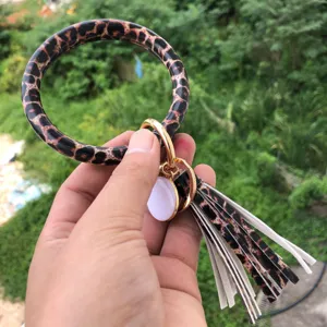 Portachiavi bracciale in pelle PU con stampa leopardata, nappina e ciondolo bianco.