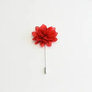 Gros plan détaillé de l'élégante broche fleur en tissu rouge, idéale pour costumes formels.