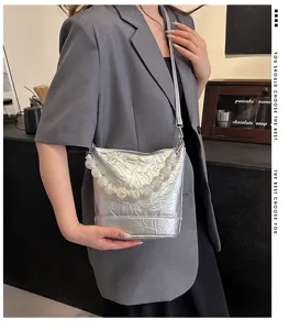Stylish silver metallic bucket bag featuring statement pearl bead handle for women fashion trend.