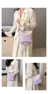 Detailed shot of a stylish light purple bucket bag with a pearl handle worn by a model.