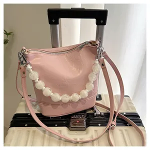 Pink bucket bag with large handmade bead handle, stylish shoulder and crossbody design for women.