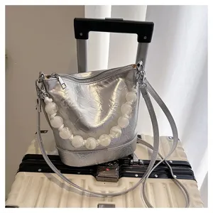 Silver bucket bag detail showcasing unique white beaded handle and metallic hardware design.