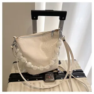 Cream white bucket bag with handmade beaded handle and crossbody strap, detail shot