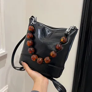 Stylish black bucket bag with amber bead handle, PU leather chic shoulder crossbody bag.