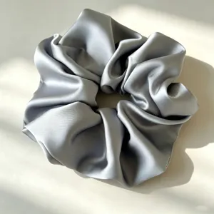 Detailopname van een glad zilveren satijnen haarelastiek, elegant design voor dagelijks gebruik.