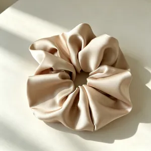 Detailopname van een gladde satijnen haarscrunchie, zachte beige stof voor dagelijks.