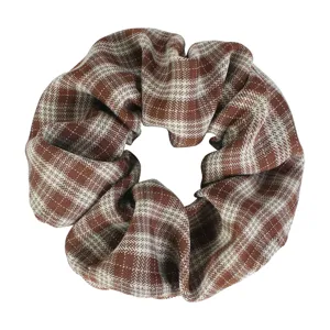Detail view of a brown and white plaid scrunchie, soft fabric with high elasticity for hair styling.