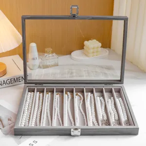 Grey wooden jewelry box with glass lid, velvet slots for pearl necklaces and bracelets.