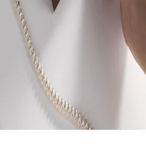 Detailed shot of elegant white pearl necklace displayed on clean white background with props.