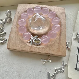 Vista dettagliata del bracciale di perle di quarzo rosa con ciondolo fiocco in legno vassoio.