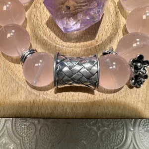 Rose quartz beaded bracelet detail with Tibetan silver woven spacer and floral charm.