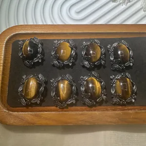 Detailed view of natural tiger eye cabochons with ornate silver leaf mountings for jewelry DIY.