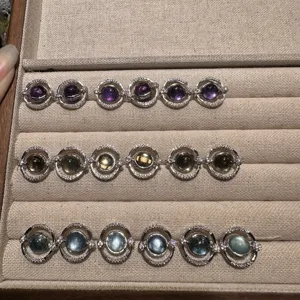 Close-up detail view of natural gemstone rotating rings set in beige jewelry tray storage box.