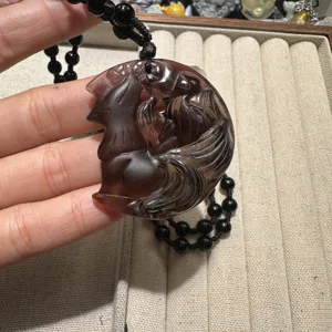 Detailed close-up of a hand-carved obsidian nine-tailed fox pendant with black beaded necklace.