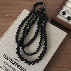 Detailed close-up shot of the elegant multi-strand black bead necklace on a styled book prop.