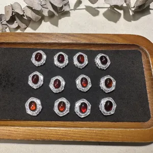 Gros plan détaillé de cabochons grenats rouges ovales avec montures hexagonales argentées.