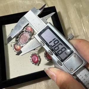 Primo piano di un cabochon in mica di litio rosa misurato con un calibro digitale preciso.