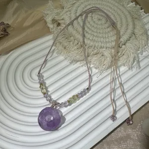 Exquisite purple crystal donut pendant necklace detail, elegant woven cord design.