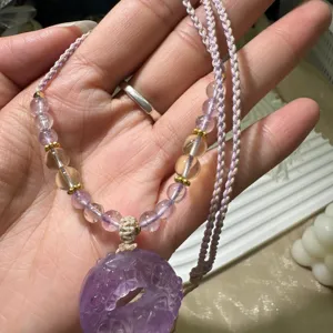 Close-up detail of natural amethyst safety buckle pendant necklace with crystal beads.