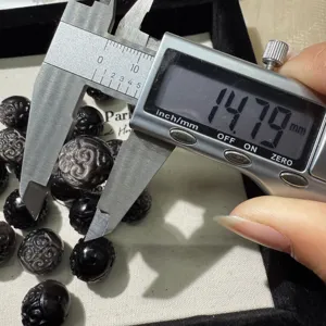 Vue rapprochée détaillée d'une perle en obsidienne sculptée avec pied à coulisse.