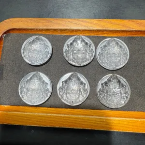 Detail shot of clear crystal carved round pendant charms with top and bottom holes for DIY bracelets.