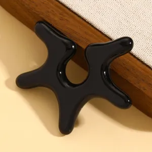 Nahaufnahme der schwarzen, unregelmäßigen Stern-Ohrklemme mit flüssigem Laufsteg-Design.